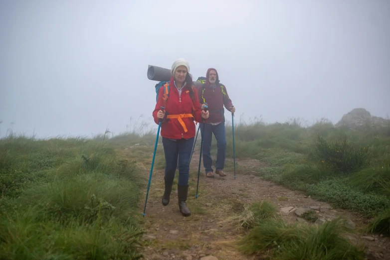 two people hiking on a path in the rain