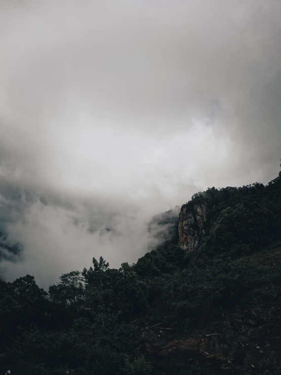 a cloudy sky over the mountains with tree tops