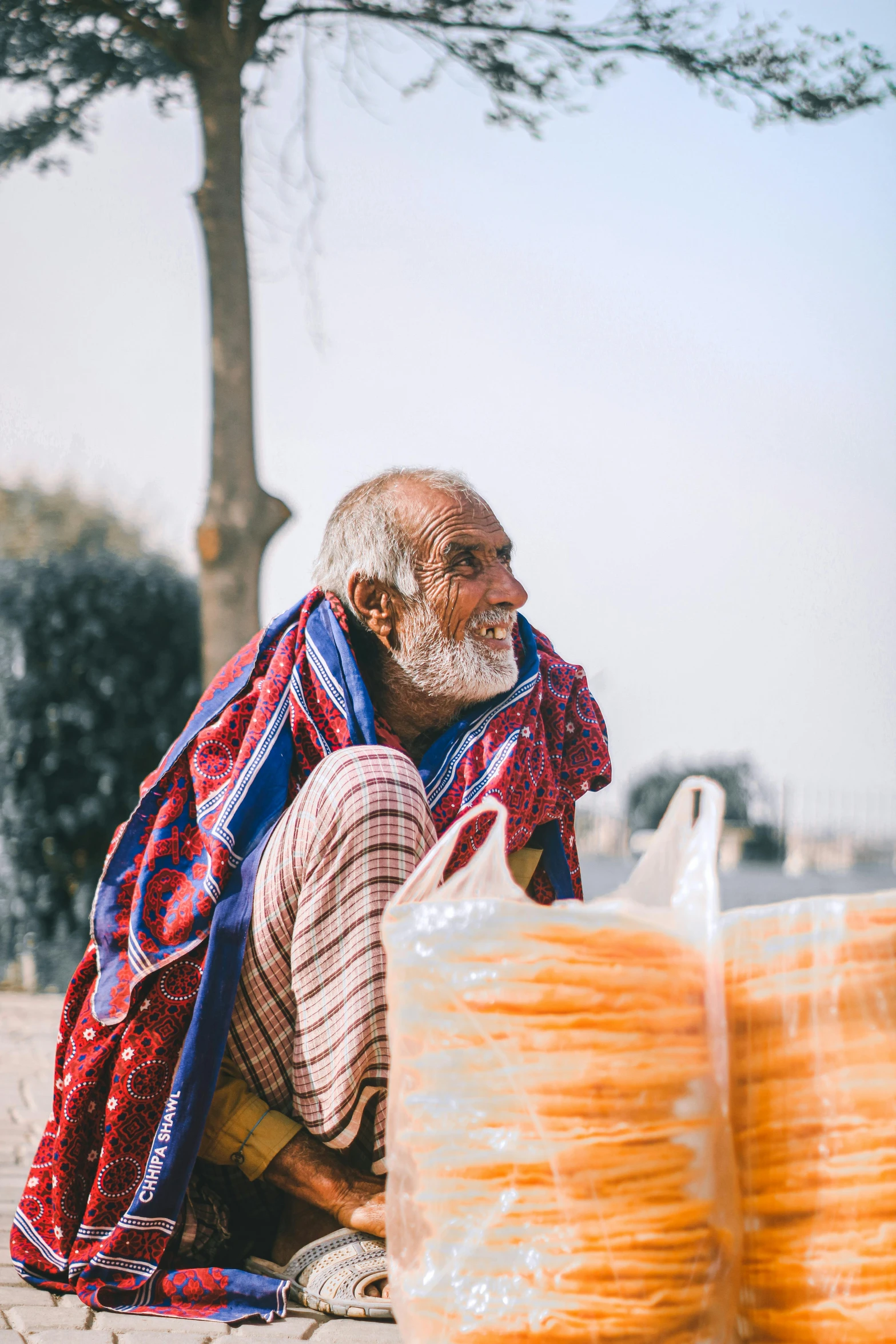 the man sits near several stacks of round bread