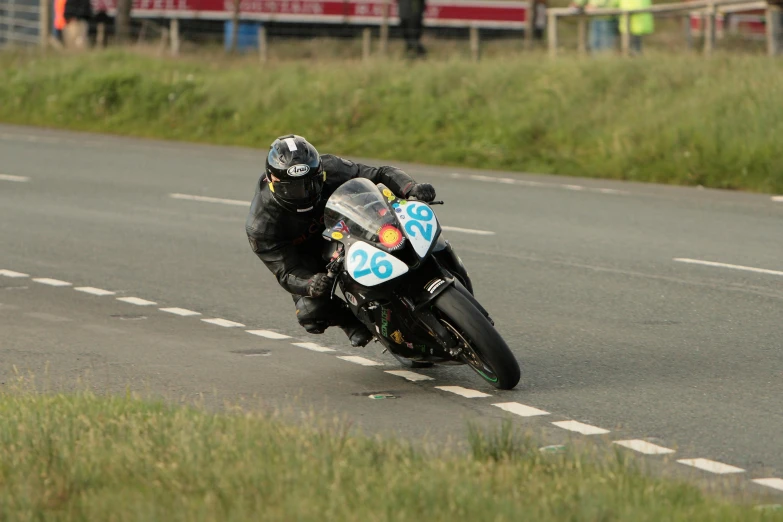 a man riding on the back of a motorcycle down a road