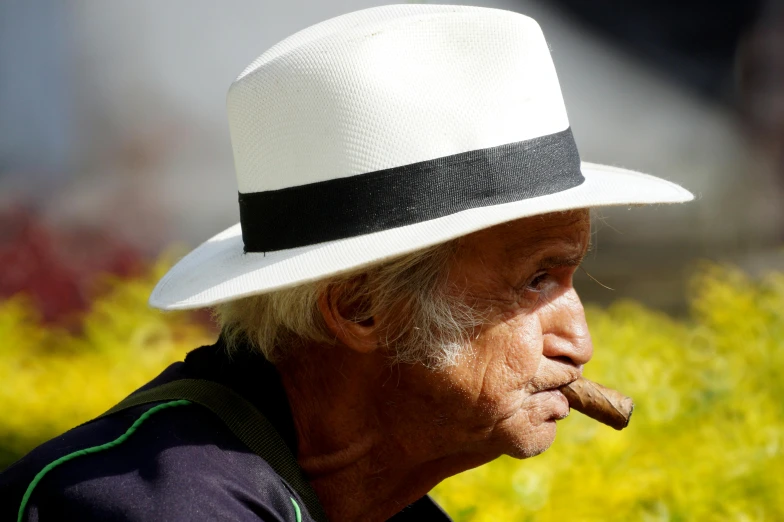 a person with a hat and cigar is looking away