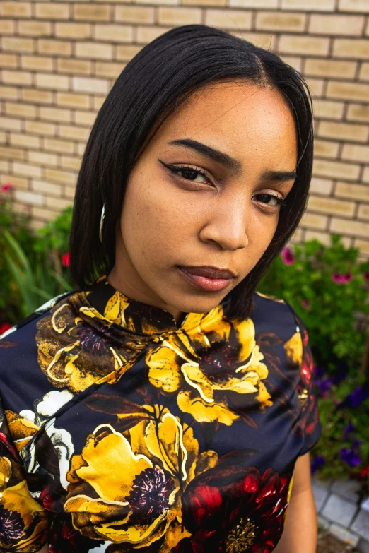 the woman wearing a black and yellow flower shirt poses for a po