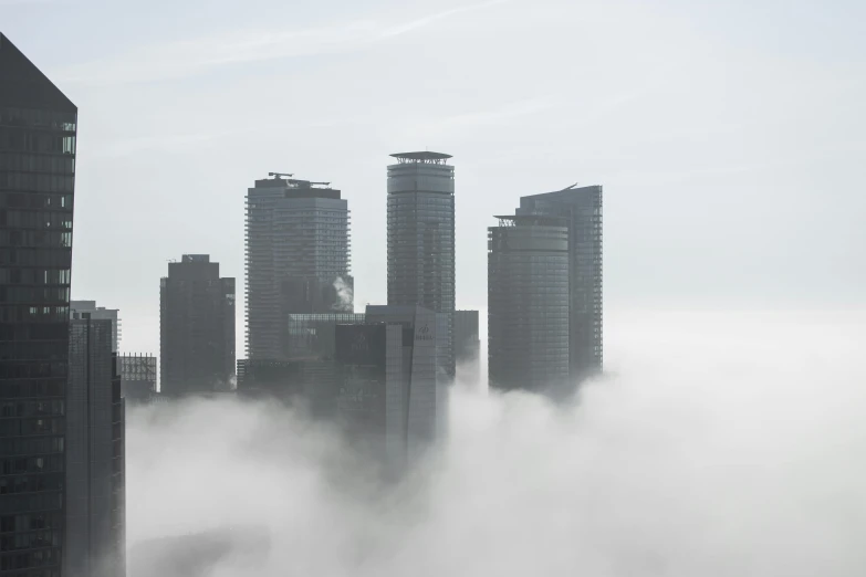 a city surrounded by tall buildings covered in clouds