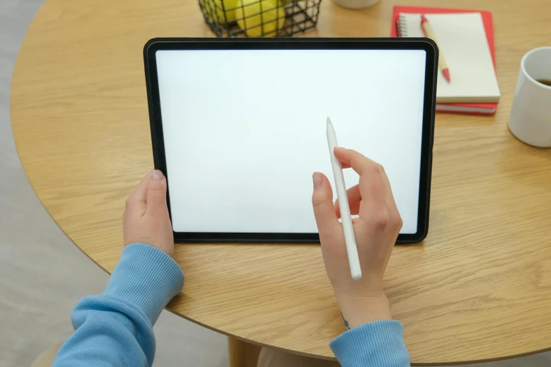 a person writing on a tablet while holding a pen