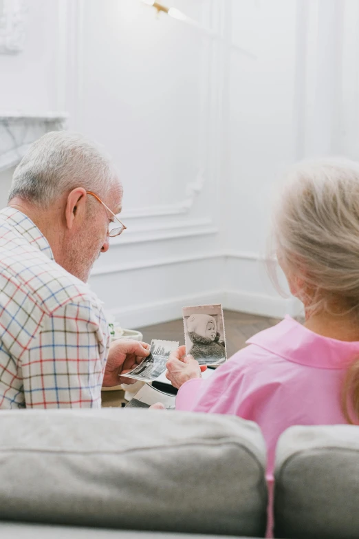 a man and a little girl on a couch with an old man looking at a po