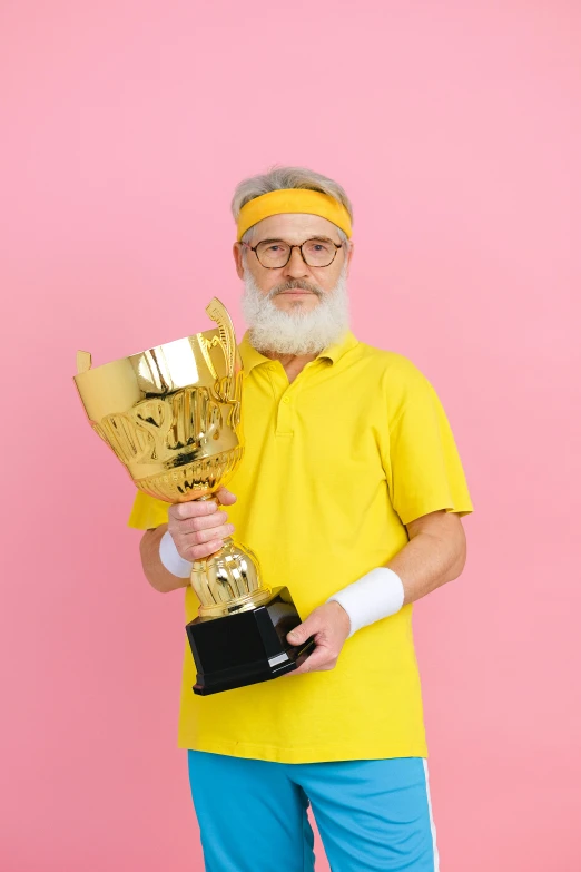 an old man in yellow holding up a trophy