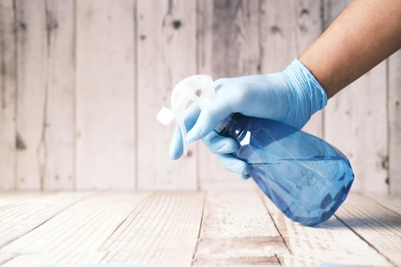 a pair of blue gloves are held up over a wooden surface