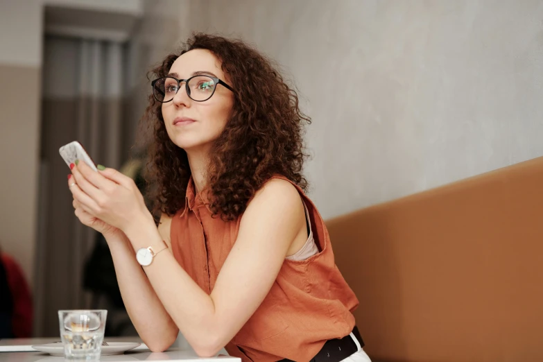 a woman sits at a table in a restaurant while looking at her cell phone