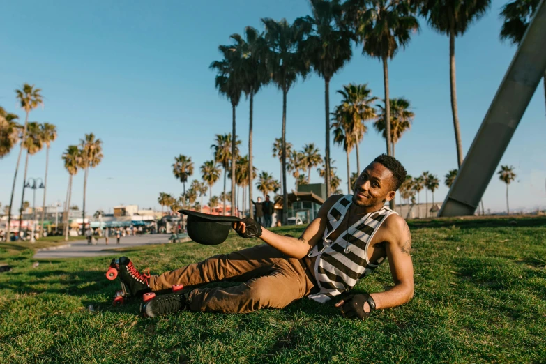 a man sitting on the grass near some palm trees