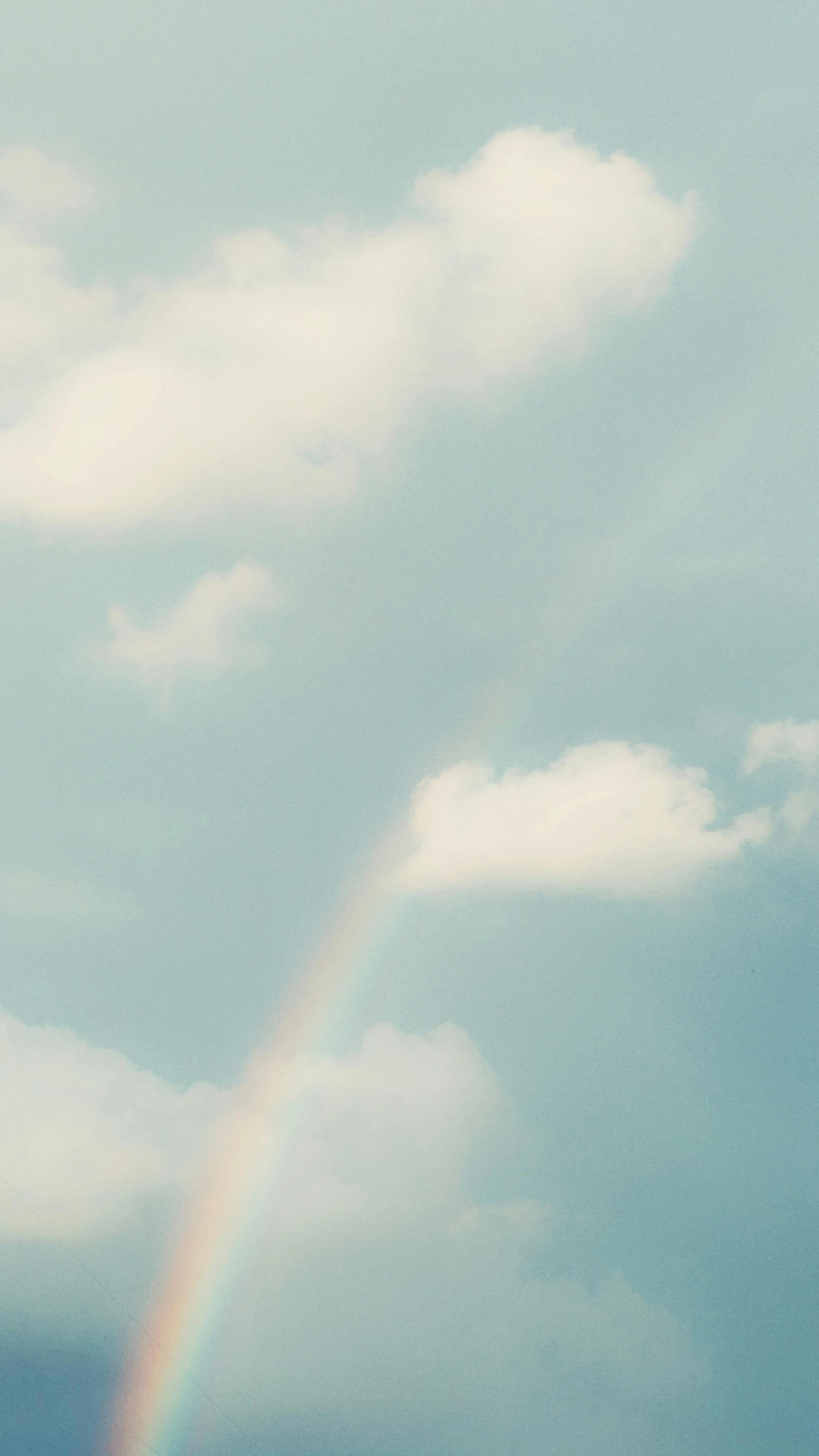 a rainbow can be seen in the cloudy sky