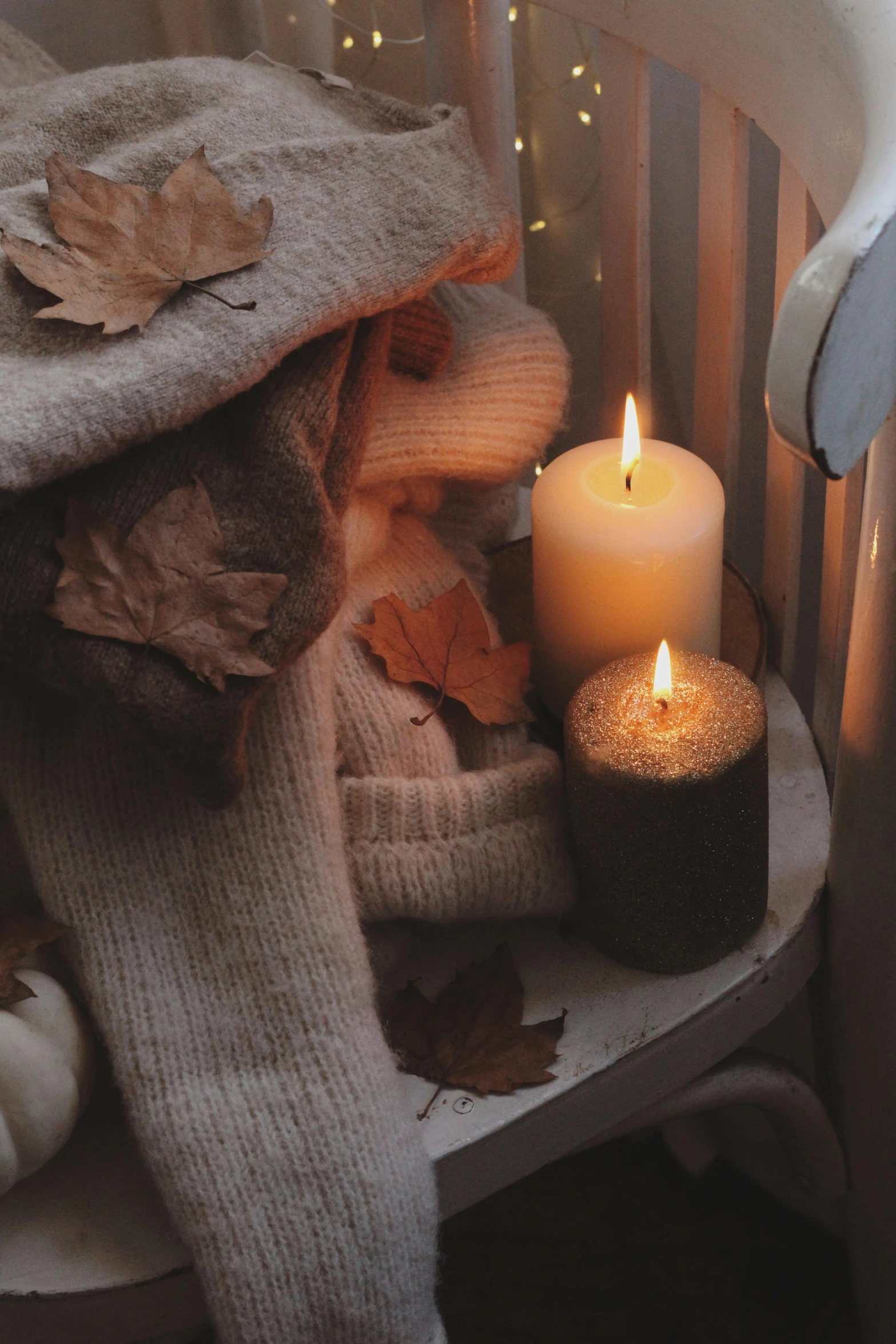 two lit candles next to some pillows and a chair