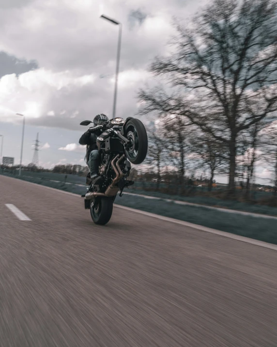 a man on his motorcycle makes an airborne trick on the road