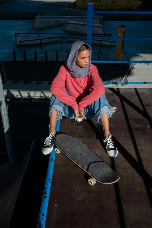 a girl sitting on a ledge with her skateboard