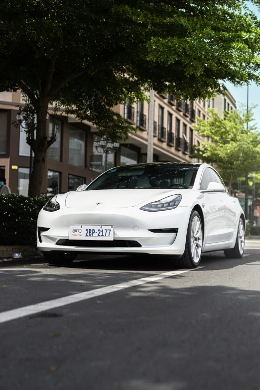 a white electric car on street near sidewalk