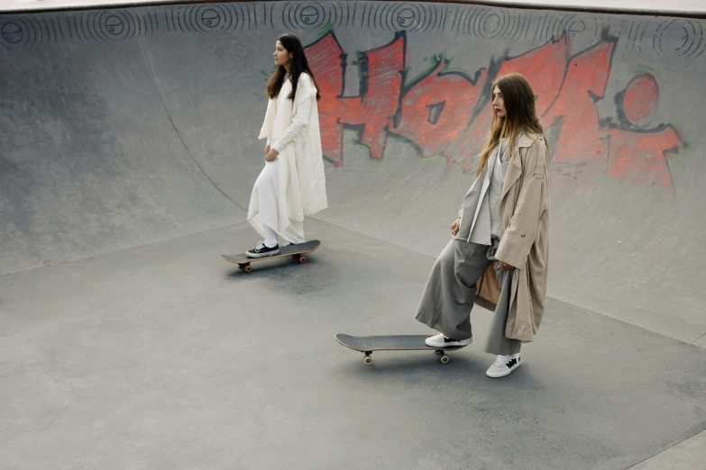 two girls are at a skate park on their skate boards