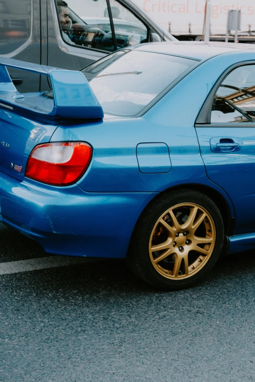 the back end of a blue car parked in the street