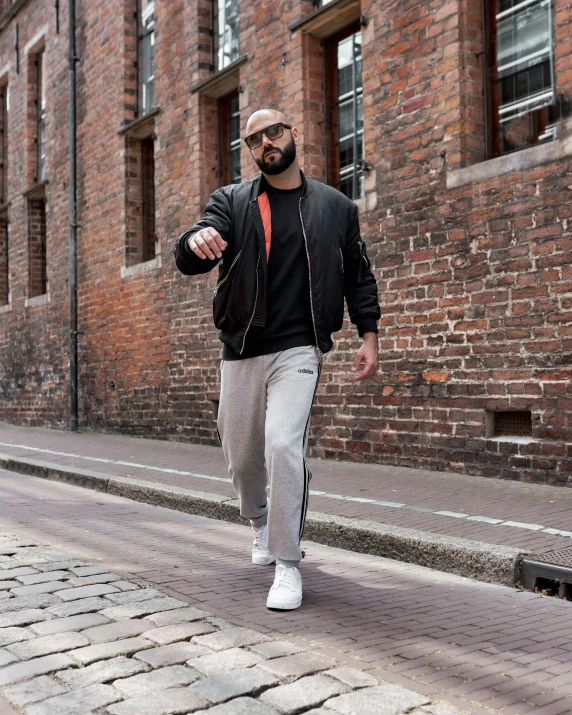 a man with glasses walking down a brick sidewalk