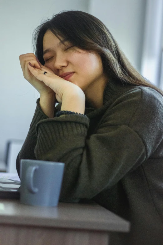 a woman with her hands near her face in a black sweater