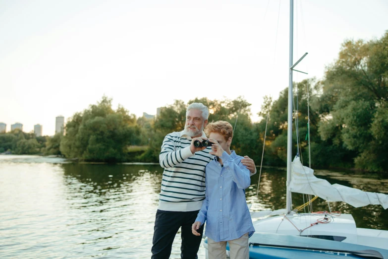 an old man and woman on the shore taking pictures with their phone