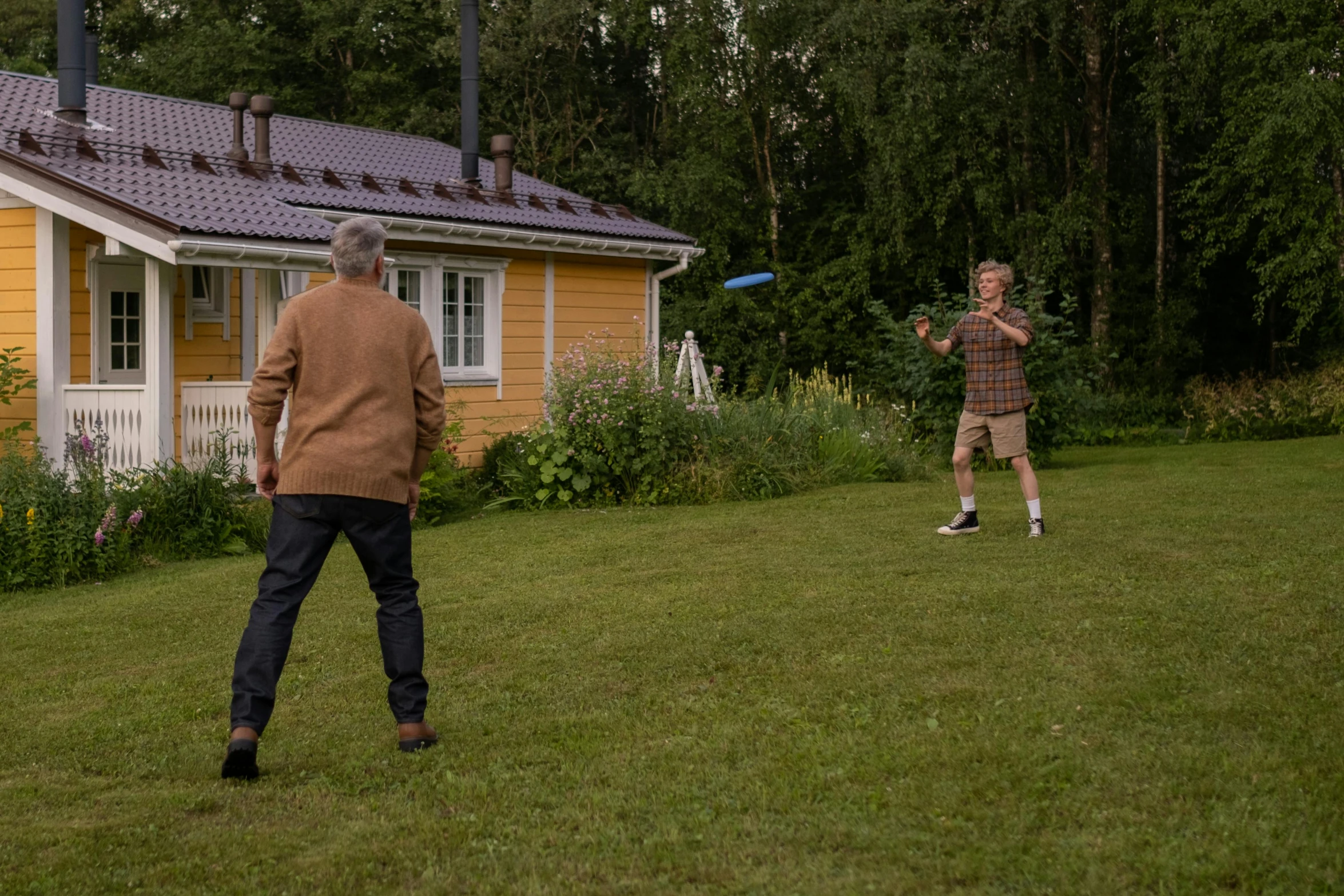 an older man and woman playing frisbee in their yard