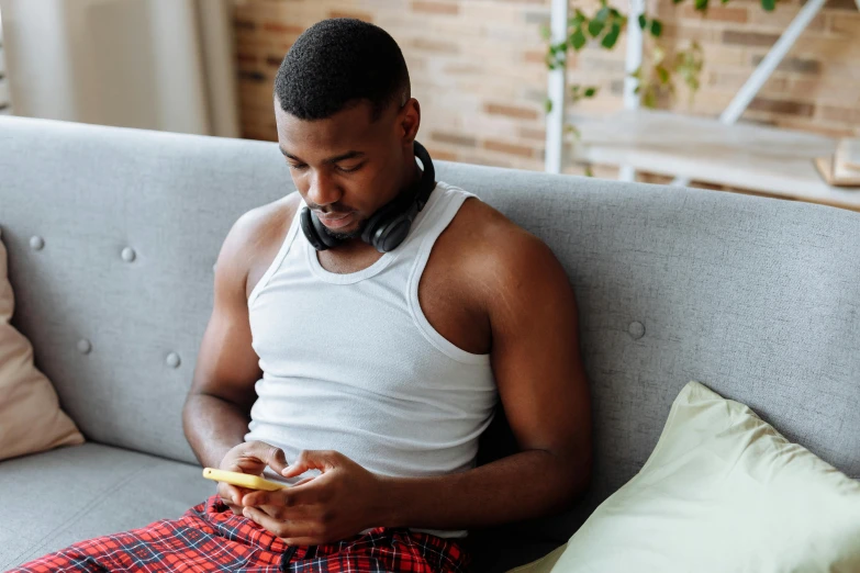 a man sitting on top of a couch looking at his phone
