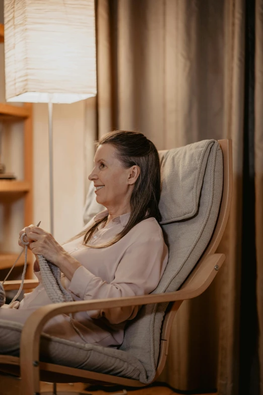 a woman sits in a chair knitting at her side