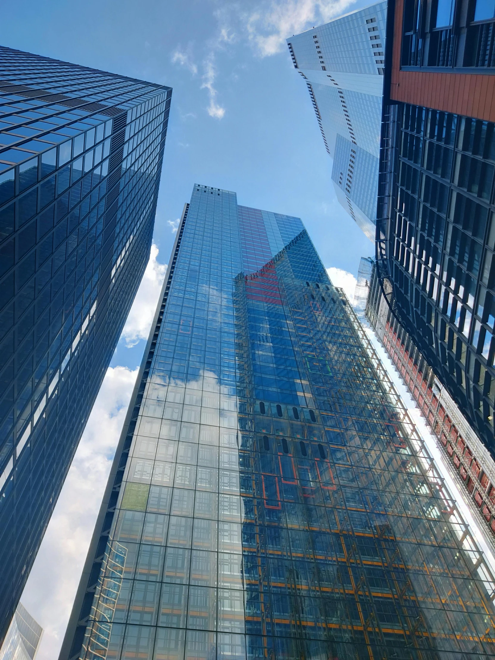 several tall buildings reflected on a glassy building facade