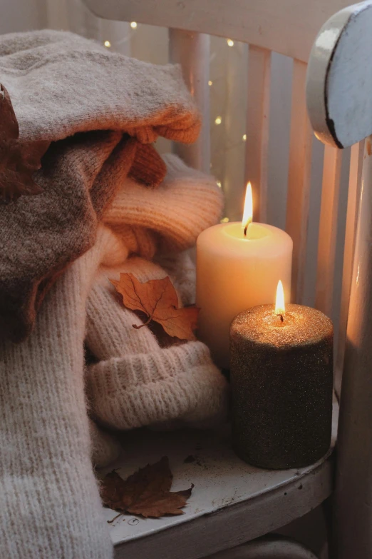 two candles with a blanket on a chair