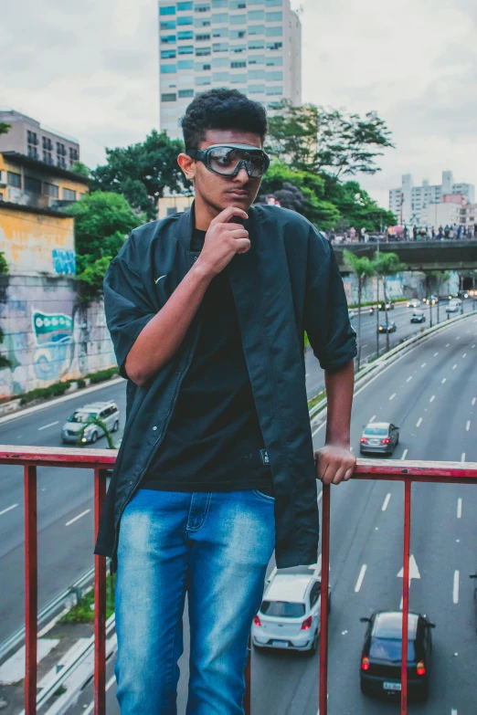 a man in dark sunglasses is standing near a railing