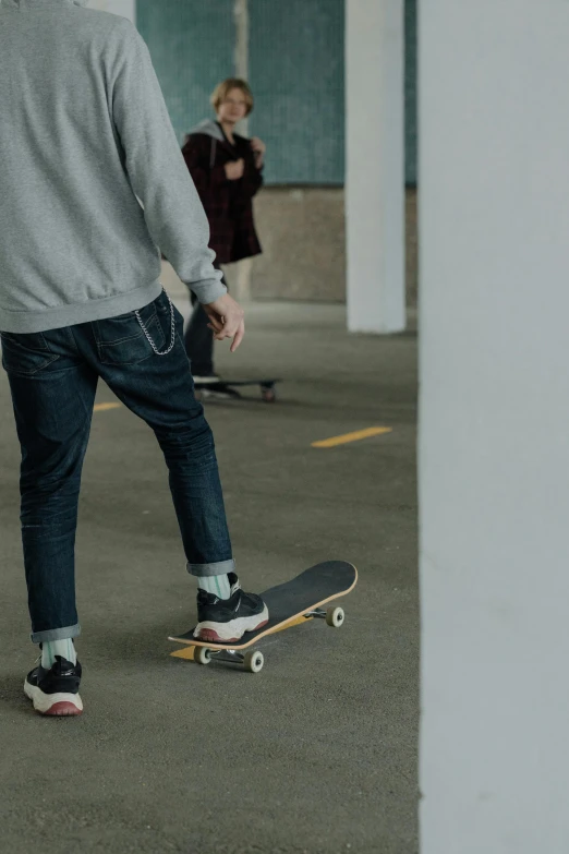 man in grey shirt and blue jeans with feet on skateboard