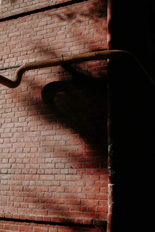an alleyway against a brick wall with a metal pipe attached to the side of it