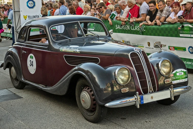 an old car drives down a city street