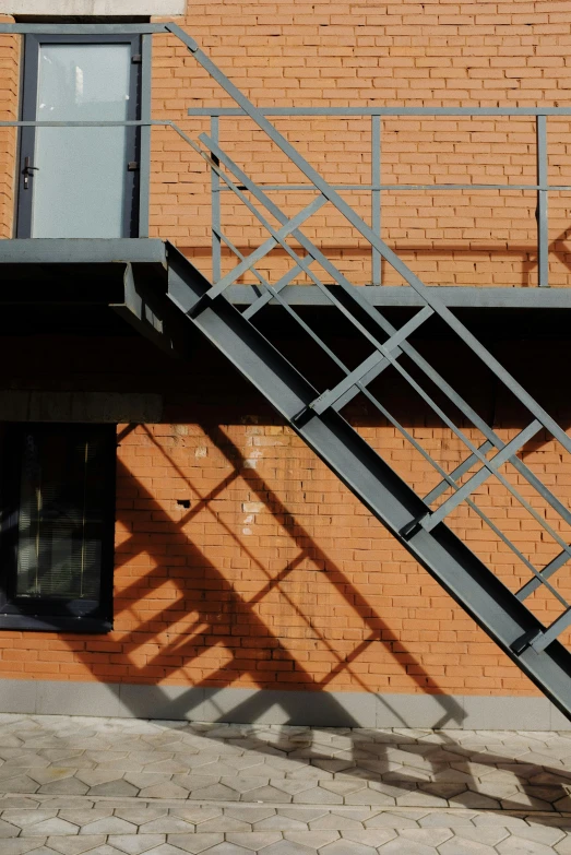 an industrial staircase with a window in front of a brick building