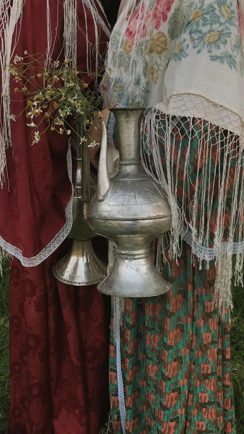 a metal tea kettle and bell with fringe on it