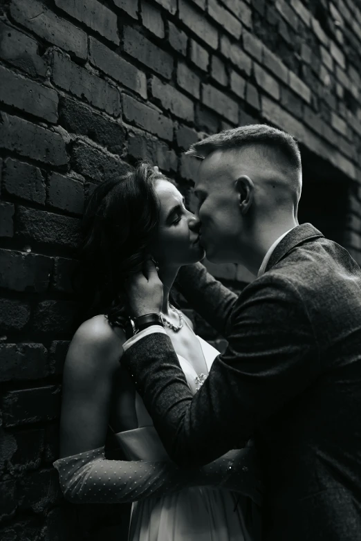 two people standing next to each other near a brick wall