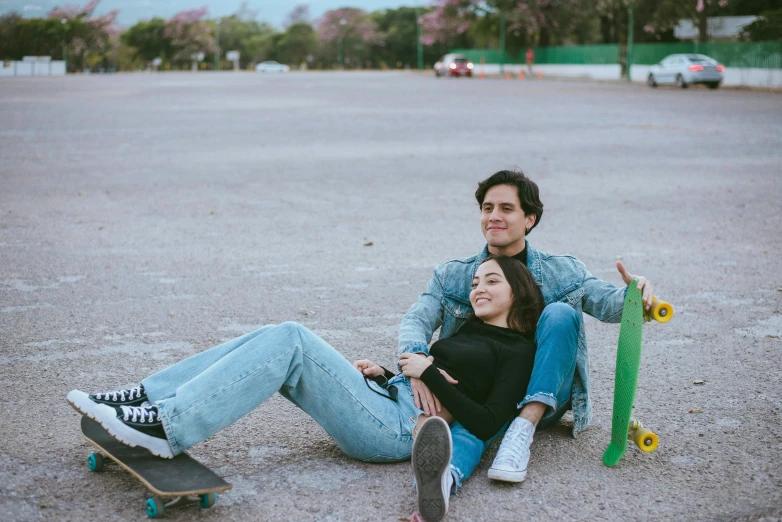 a couple siting on the street with their skateboards