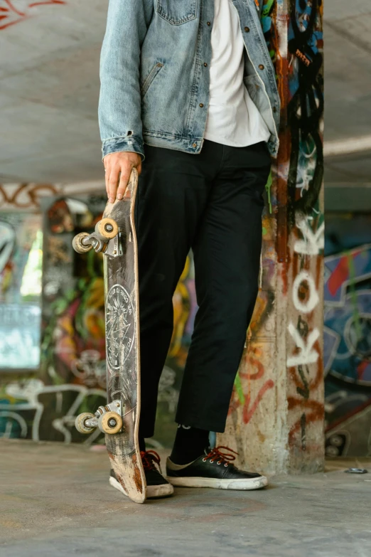 a young man in denim jacket holding a skateboard