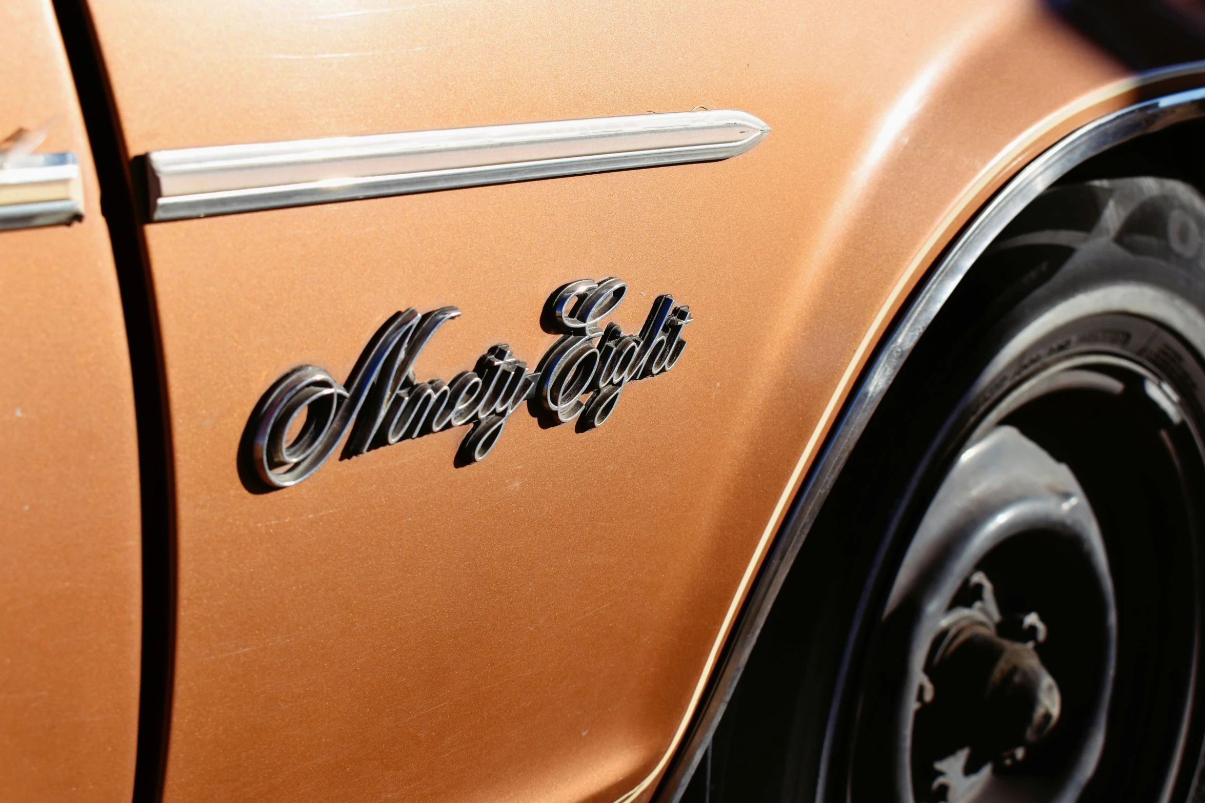 a small orange classic car parked on the street