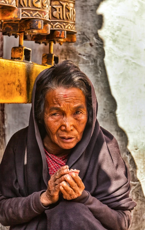 the woman is dressed in traditional clothing standing by an oriental bell