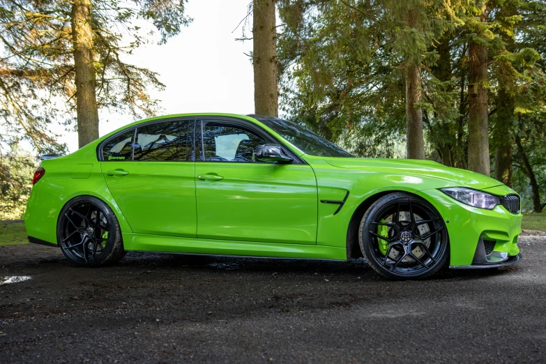 the green car is parked in front of the trees