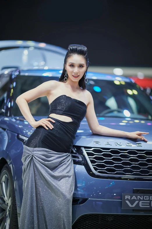 a girl in an elegant dress stands next to a vehicle