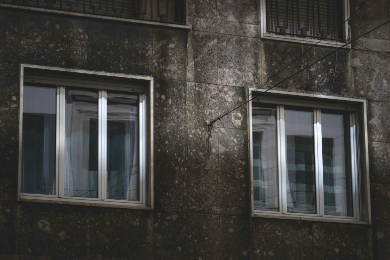 two windows in a large dark building with no blinds