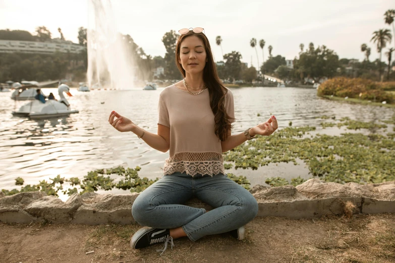 a girl sitting in the water meditating while looking at water