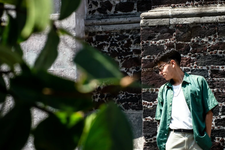 a man is posing next to a brick wall