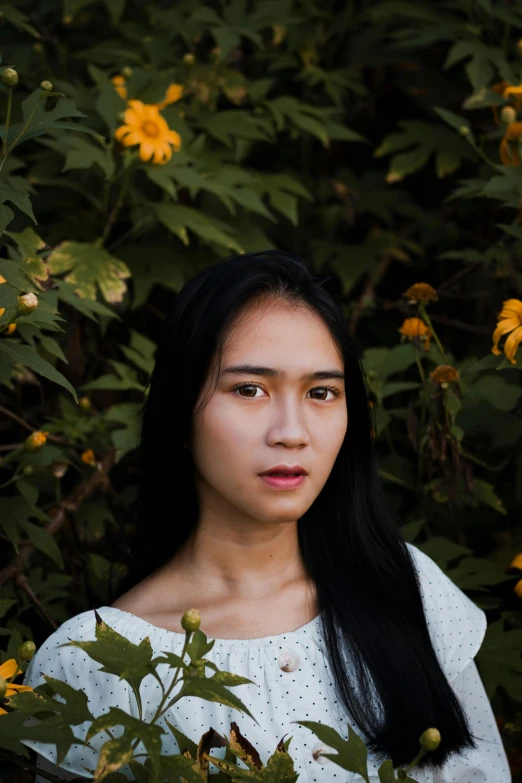 a girl standing in front of some flowers