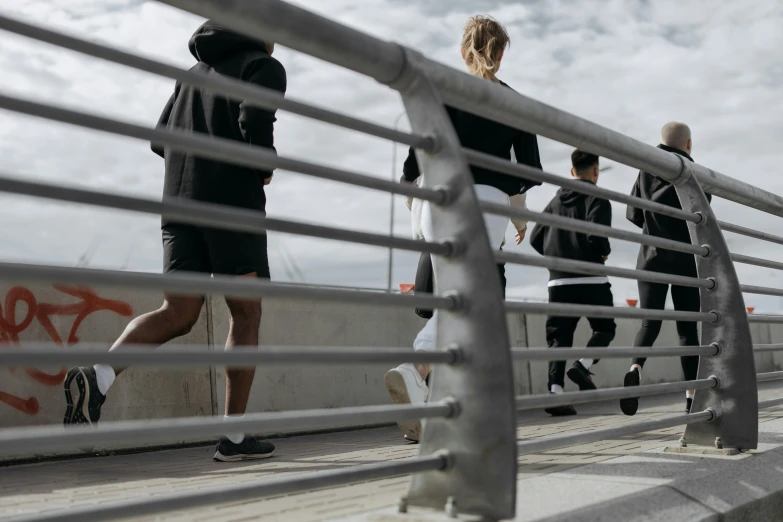 several people walking on the bridge and another person has their hand on his hips