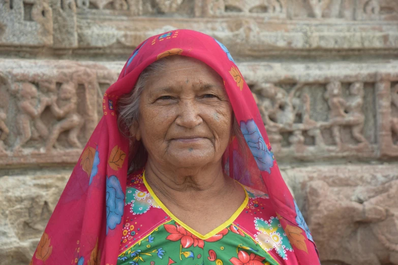 an old lady in a colorful sari looks into the camera
