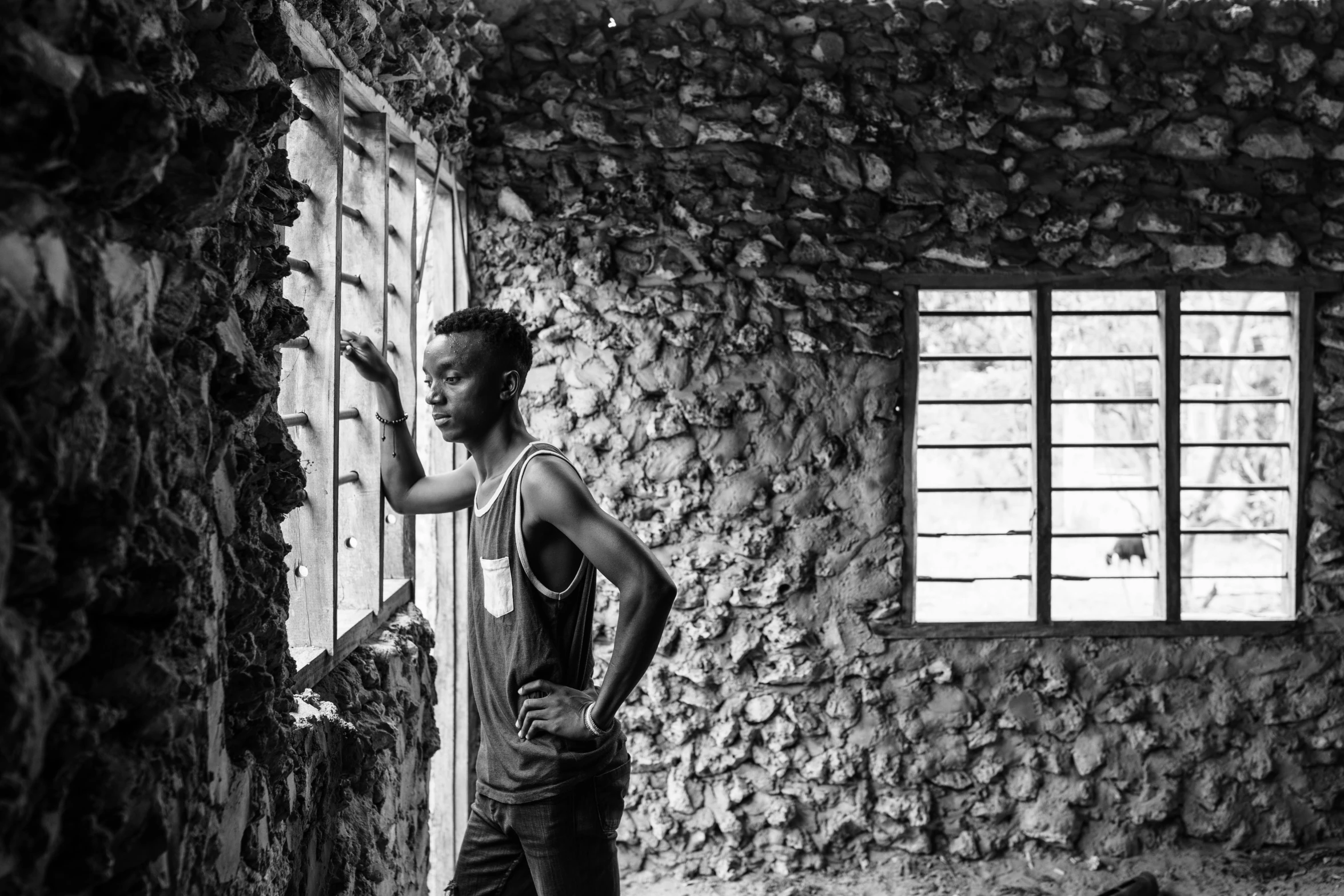 a man standing in an abandoned building pointing to soing off the window