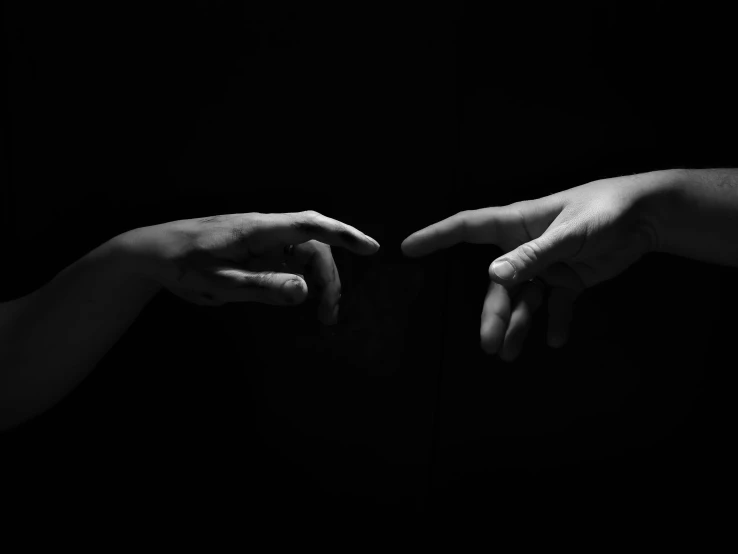 two hands reaching toward each other in the dark