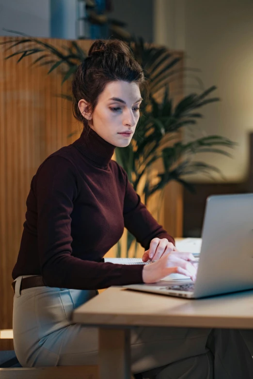 woman sitting in chair working on laptop and writing